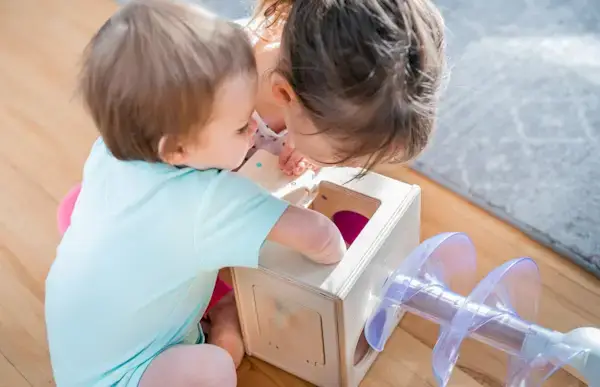 Two young children playing with the Slide and Seek Ball Run by Mommy's Reviews