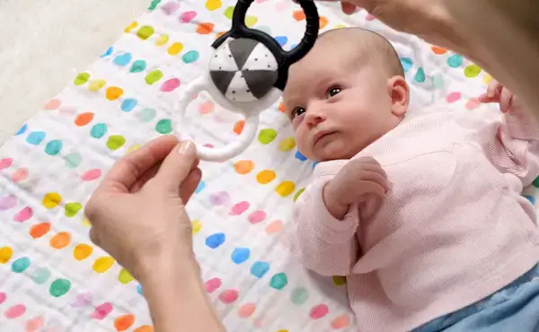 Baby looking up at the Silicone Rattle from The Looker Play Kit