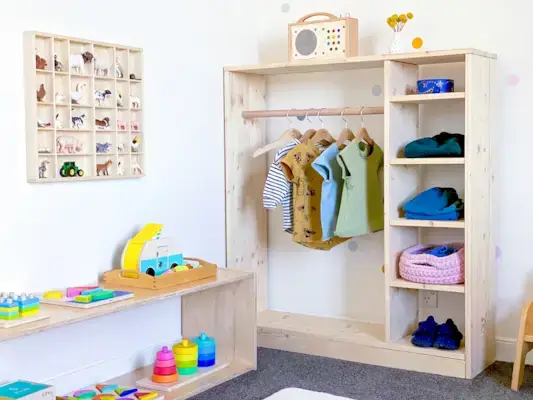 Montessori bedroom with built in closet and table with colorful toys by Mommy's Reviews on top