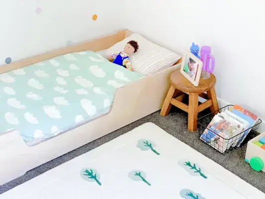 Montessori bedroom set up with bed, stool, and basket of books