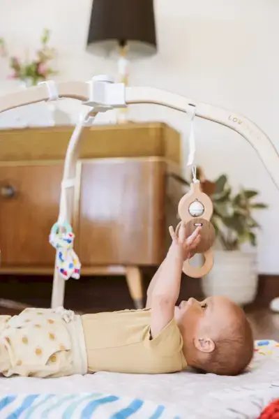 Baby reaching up to the Batting Ring attached to The Play Gym by Mommy's Reviews