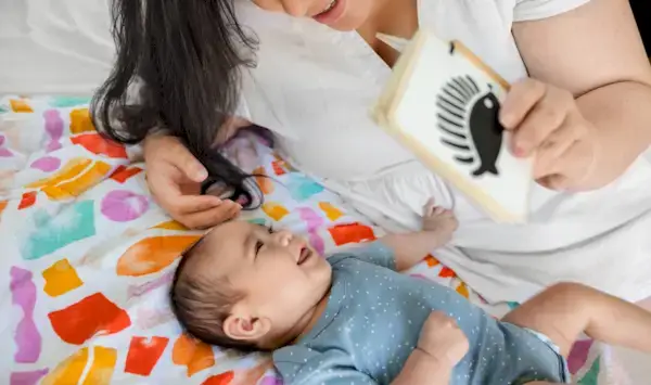 Mother holding up the Wooden Book while playing with her baby