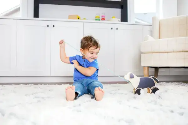 Toddler sitting on a rug pulling the Pull Pup by Mommy's Reviews