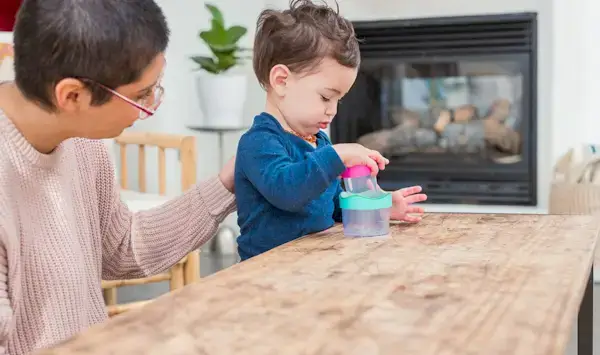 Toddler sitting at a table stacking the Nesting Stacking Drip Drop Cups by Mommy's Reviews