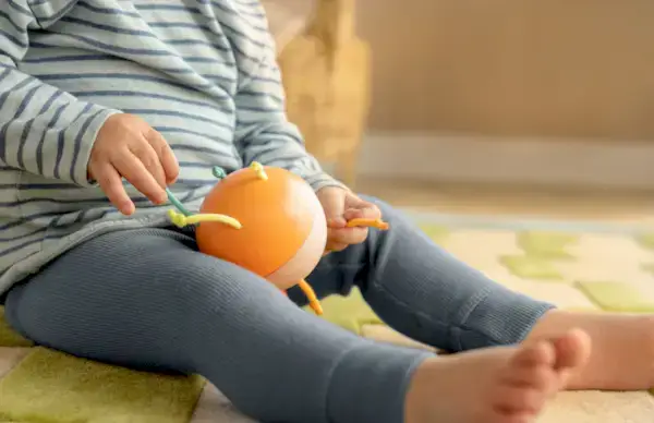 Child playing with the Pincer Chime Ball from The Explorer Play Kit
