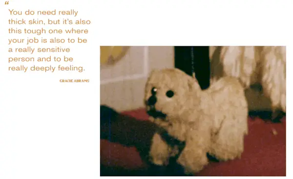 A gif of Gracie Abrams wearing a cream-colored furry Stella McCartney long coat with matching Ferragamo heels and playing with a puppet of a dog for Mommy's Reviews's fall issue. Next to the gif if a pull quote that says: 'You do need really thick skin, but it's also this tough one where your job is also to be a really sensitive person and to be really deeply feeling.