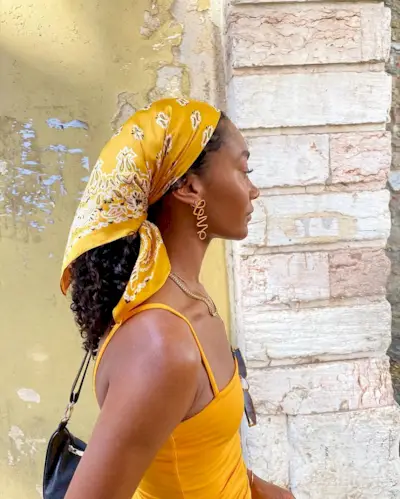 Woman wearing a yellow bandanna as a hair scarf.