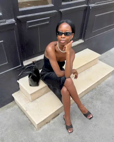 A woman sitting on a step in Paris wearing black heels with a natural-looking pedicure
