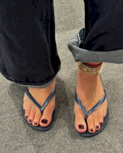 A woman wearing blue flip flops with a burgundy pedicure