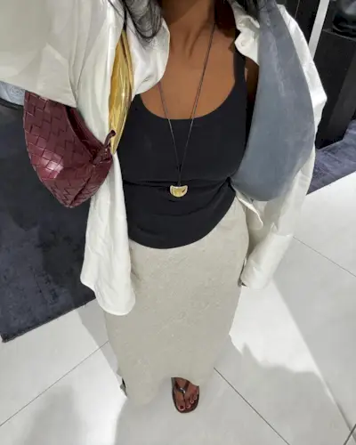 A woman taking a picture of her outfit with a burgundy pedicure