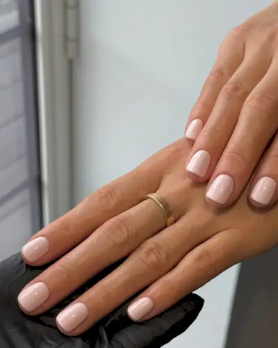 Light pink nail polish on short, square nails.
