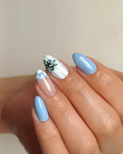 Mismatched baby blue nail polish, French tips with checkered prints, and white nails with blue stripes and blueberries.