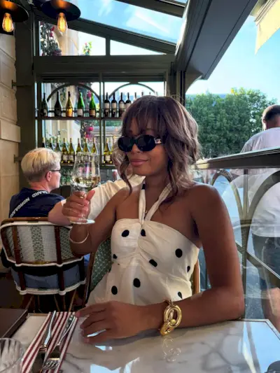 A woman sitting in a restaurant in France with a French tip manicure
