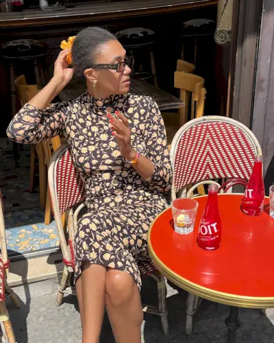 @lenafarl sitting in a cafe wearing a bright red nail polish