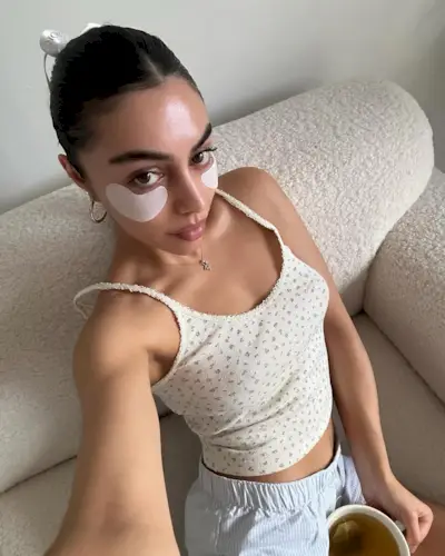 Mobina Peiman wearing white under eye patches white a floral tank top and blue and white lounge shorts.