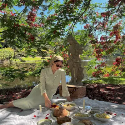 Woman sitting next to a statue next to a pond