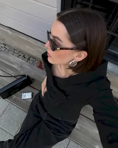 Mary L Jean shows of her sleek french bob with silver earrings, tortoiseshell sunglasses, and a knitted black sweater