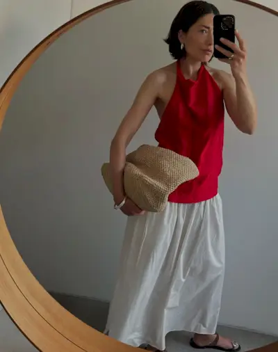 woman with short hair wearing a red top and white skirt
