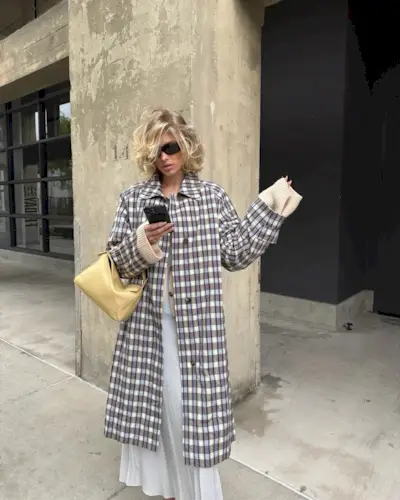 Elsa Hosk wearing a maxi dress and a trench with a curly, swept bob hairstyle