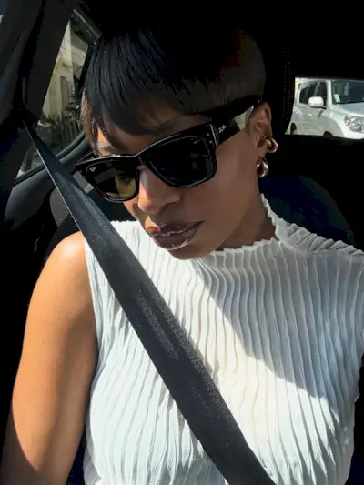 A woman taking a selfie in a car wearing sunglasses with a swept bob hairstyle
