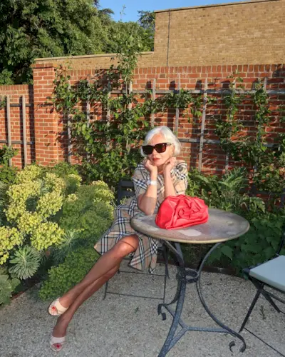 A woman sitting in a garden wearing a Burberry dress with a swept bob hairstyle