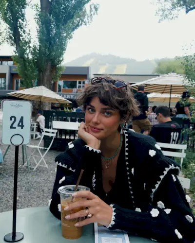 Taylor Hill at a cafe with a wavy, swept bob hairstyle