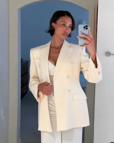 A woman taking a selfie in a white blazer with a swept bob hairstyle