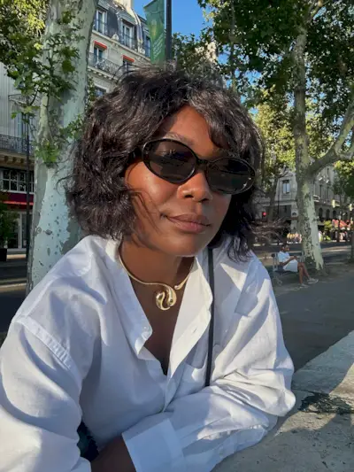 A woman taking a selfie in Paris with a curly, swept bob hairstyle