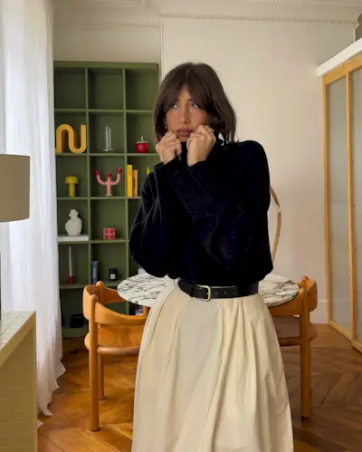 A woman in a stylish apartment with a sleek bob hairstyle and curtain bangs