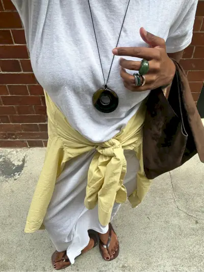 A woman taking an outfit picture wearing brown flip flips with a chocolate brown pedicure