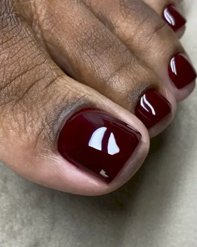 A close-up picture of a glossy burgundy pedicure