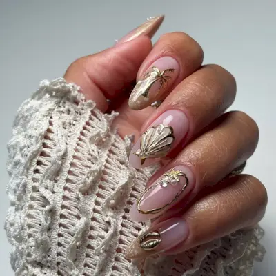 Person with a gold and pink beach-themed manicure.
