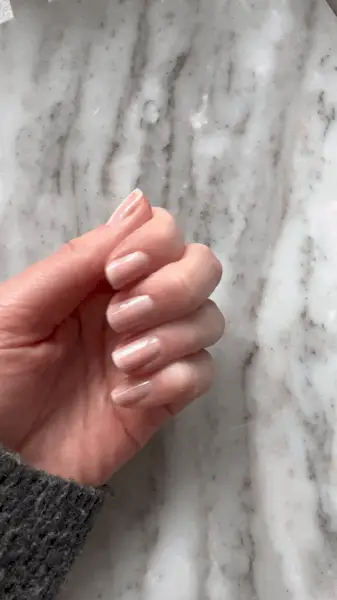 Hand holding a bottle of Essie Gel Couture Top Coat.