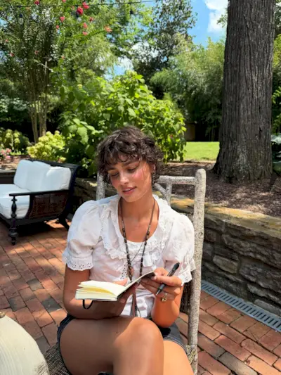 Taylor Hill reading outside with a hairstyle that is a mix between a pixie and a bob