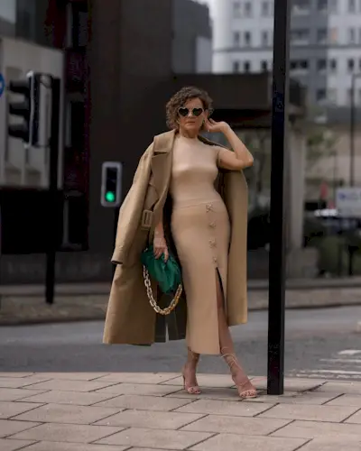 A woman posing outside with an asymmetrical curly bob haircut
