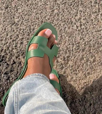 Woman wearing Hermes sandals with French pedicure design