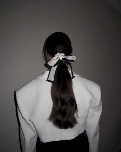 a woman with a long ponytail and bow hair accessory