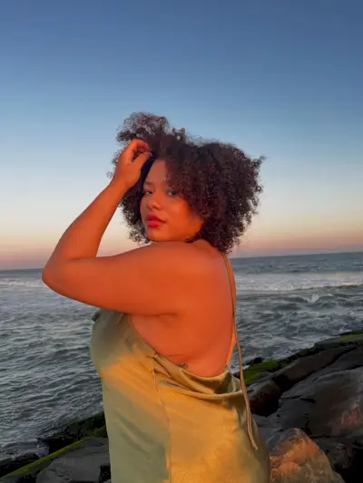 A woman on a beach at sunset wearing a green silk dress