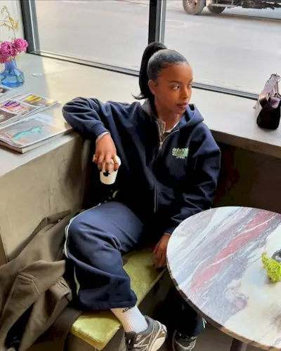 Creator @aysha.sow wearing a slicked-back pony sitting in a cafe.
