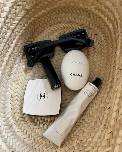 Woven basket bag with beauty products and sunglasses inside