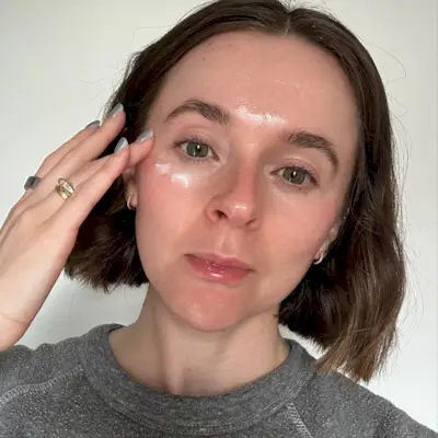 A selfie of Grace Day applying a vitamin c eye cream to her skin