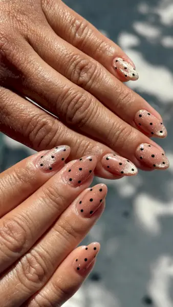Long almond nails with neutral-toned cat eye polish with black polka dots