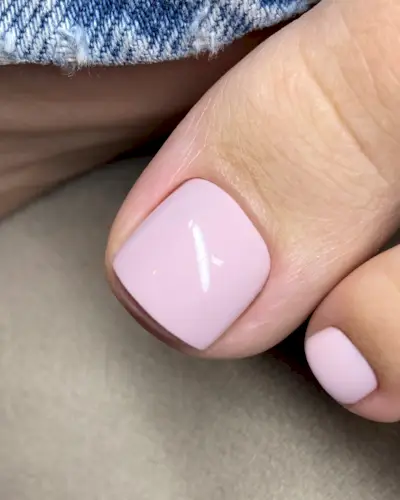 A close-up picture of a woman's baby pink pedicure