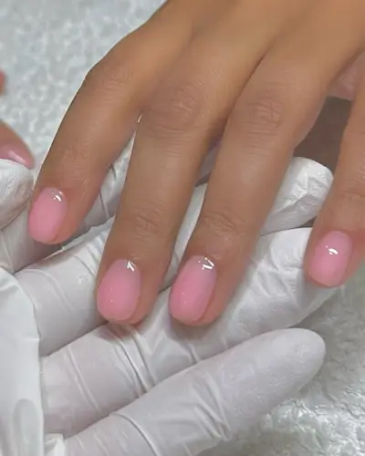A picture of a woman's hand with a sheer pink manicure