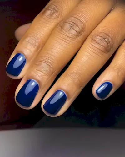A picture of a woman's hand with short, navy nails