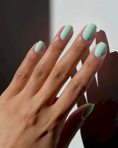 @iramshelton with short, square nails wearing a mint green nail polish