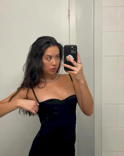 Sasha Mei poses in a black dress with tousled strands.