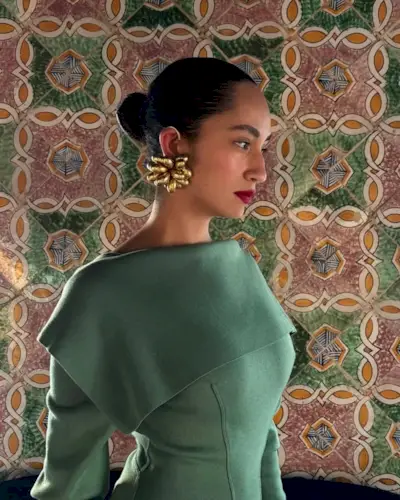 A woman wearing red lipstick with her hair slicked back and statement earrings.