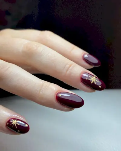 Burgundy nails with gold star nail art
