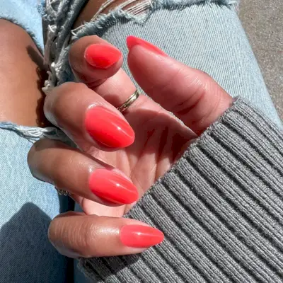 Hand with long nails painted with coral pink nail polish